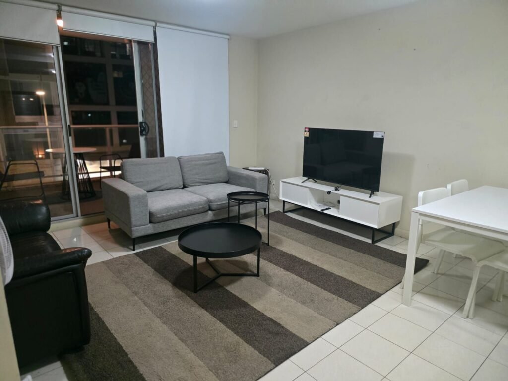 Living room with sofa, TV unit and dining table, Parramatta apartment